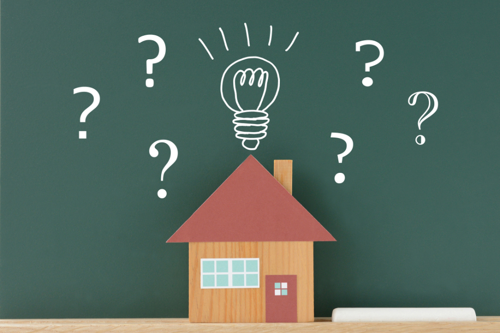 Drawing of a house with a light bulb on top of it and question marks around it.