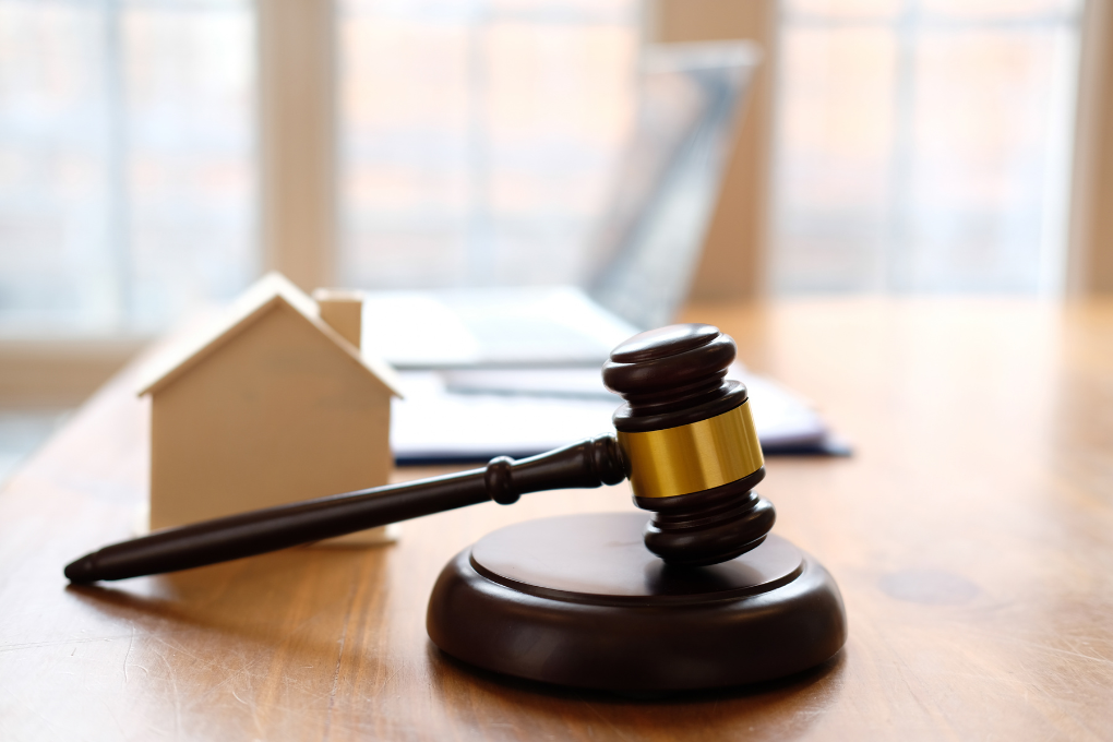 Gavel and small house on a table, representing housing legislation.