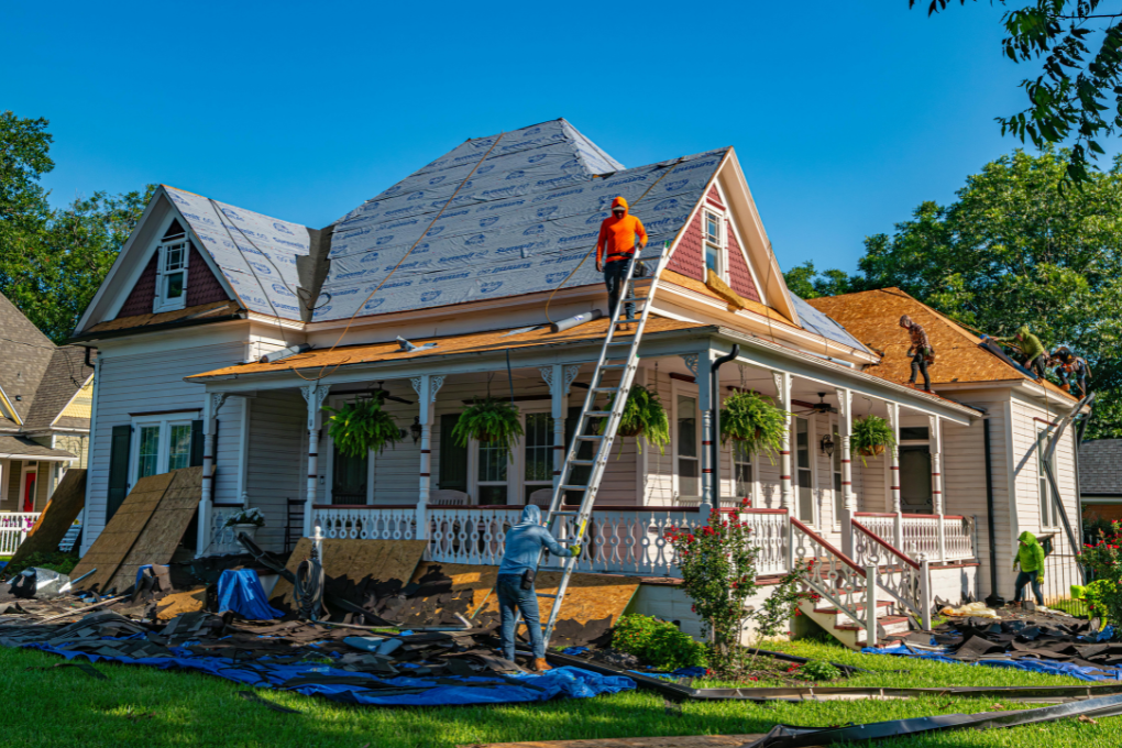 Contractor standing on roof of house undergoing a renovation.